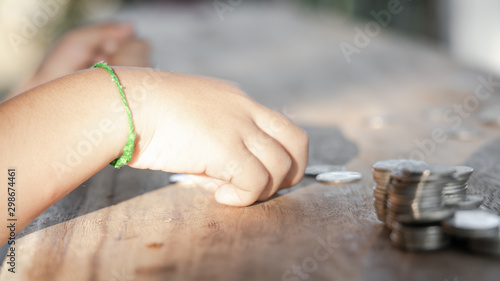 The boy hand holding money coin and stack with layered coin is much more. Business and Finance concept. Money saving concept.