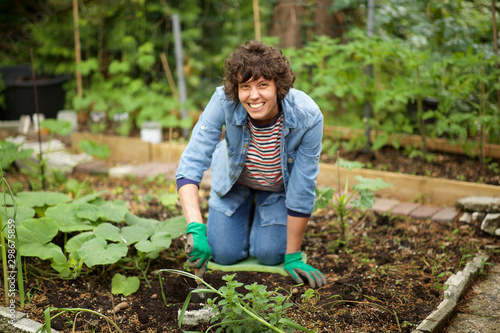  smiling woman on knees digging in garden soil
