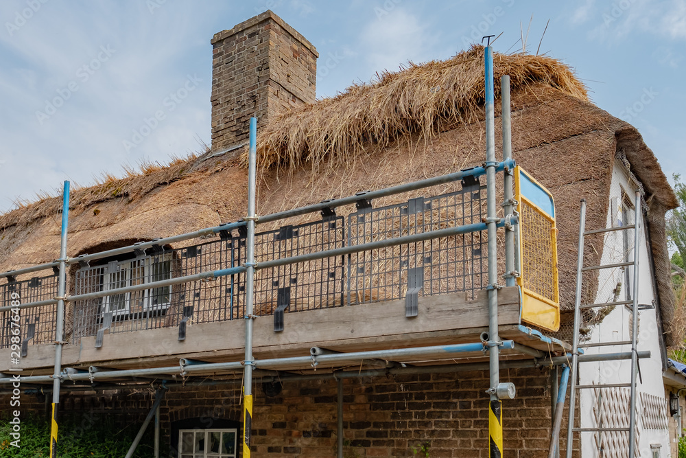 Part completed thatched roof renovation seen on an old english cottage