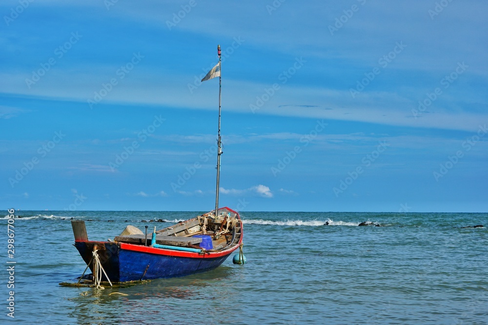Fototapeta premium Fishing boat floating in the sea with blue sky.