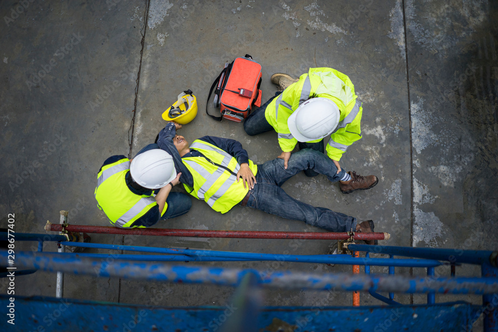 Fototapeta premium Basic first aid training for support accident in site work, Builder accident fall scaffolding to the floor, Safety team help employee accident.