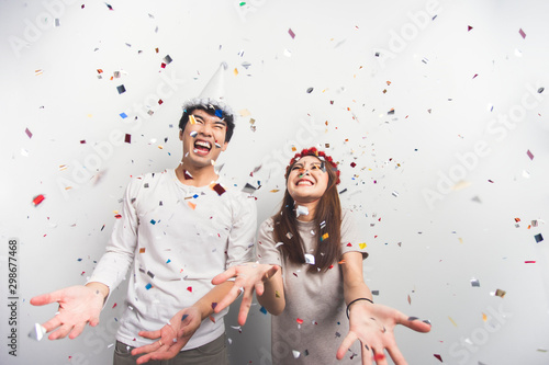 Two Asian people have fun celebrating Christmas or New Year party confetti together.