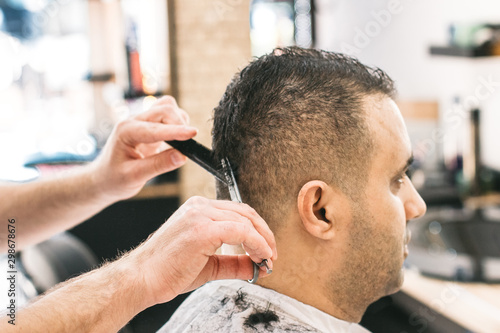 Barber making stylish haircut with professional scissers in barber shop. Hair cut for turkish man