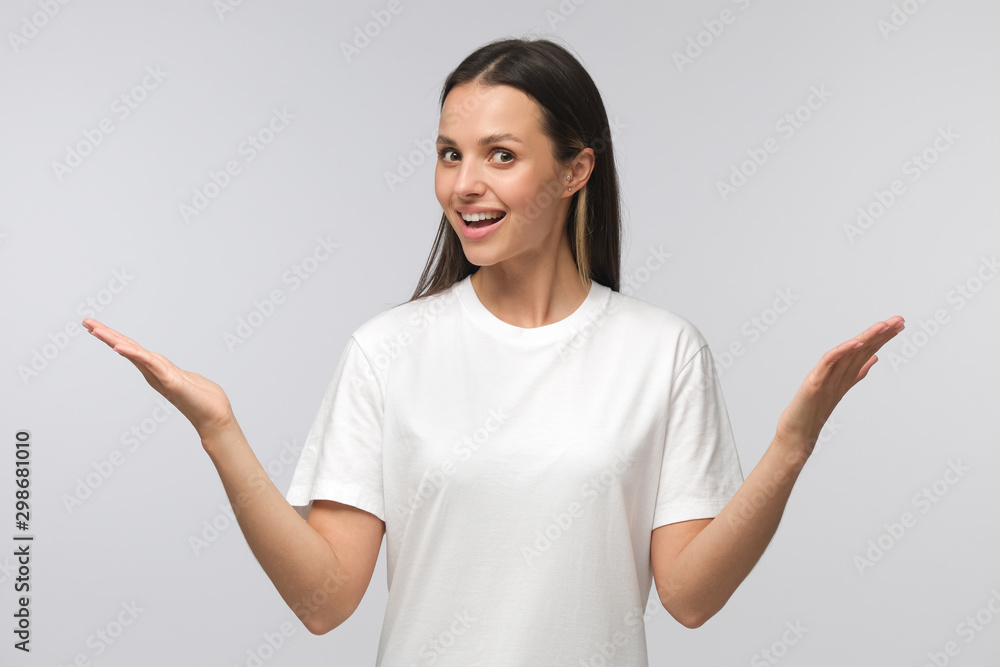 Photo of good-looking girl isolated on gray background spreading arms as if interested and wondering what to choose Photo of good-looking girl isolated on gray background spreading arms as if interested and wondering what to choose