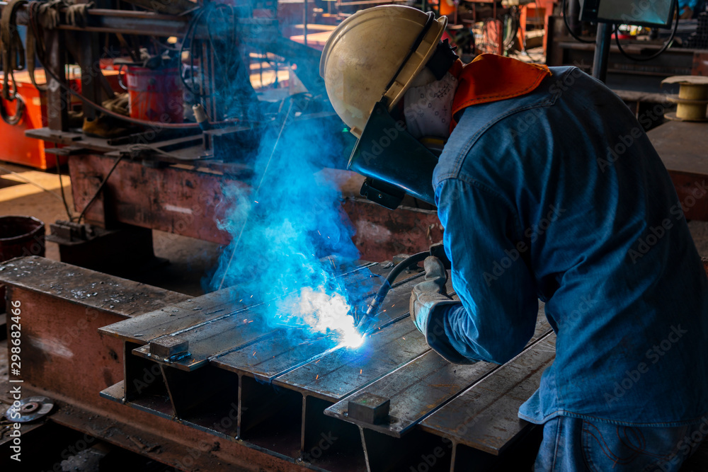 The welder is welding a steel structure with the process Flux Cored Arc  Welding (FCAW) in Industrial factory. Stock-Foto | Adobe Stock