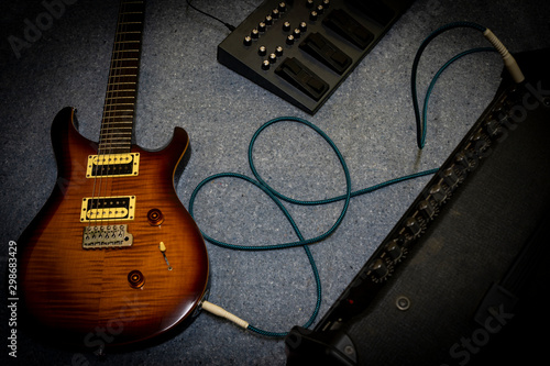 Top view electric guitar, effect and amplifier on gray carpet background.