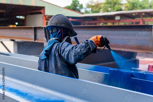 The painter is working to painting the steel structure with spray gun, at Industrial factory.	