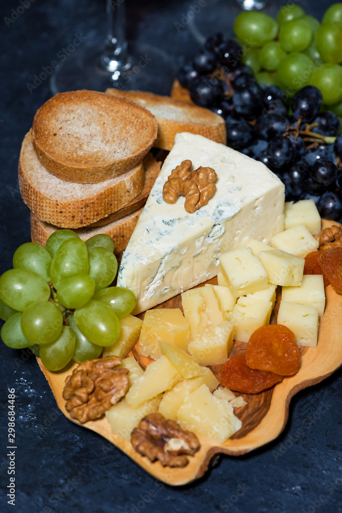 cheese platter on a wooden board, bread and fruit, vertical cheese platter on a wooden board, bread and fruit, vertical