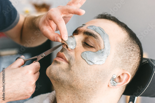 Hair cutting in the nose of a man. Male face waxing. Barber removes hair by shugaring from the face of turkish man.