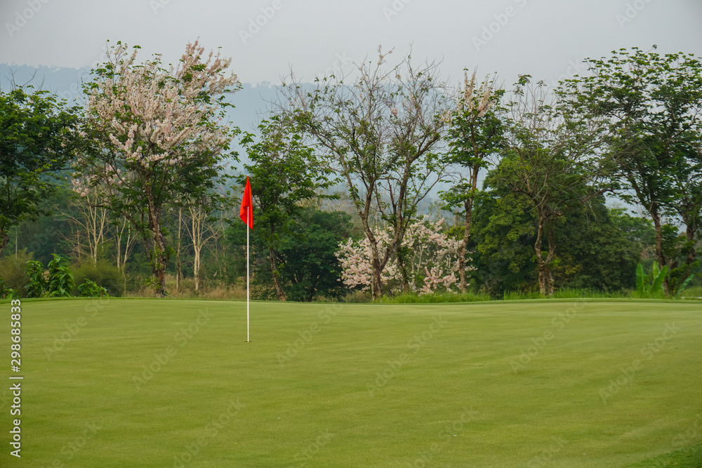 Obraz premium Red flag on Green Golf Course and Green Mountain.