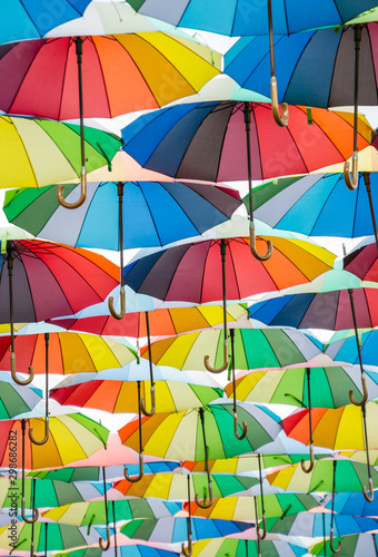 a collection of open umbrellas floating in the air, each umbrella is painted in all colors of the rainbow, photographed from below