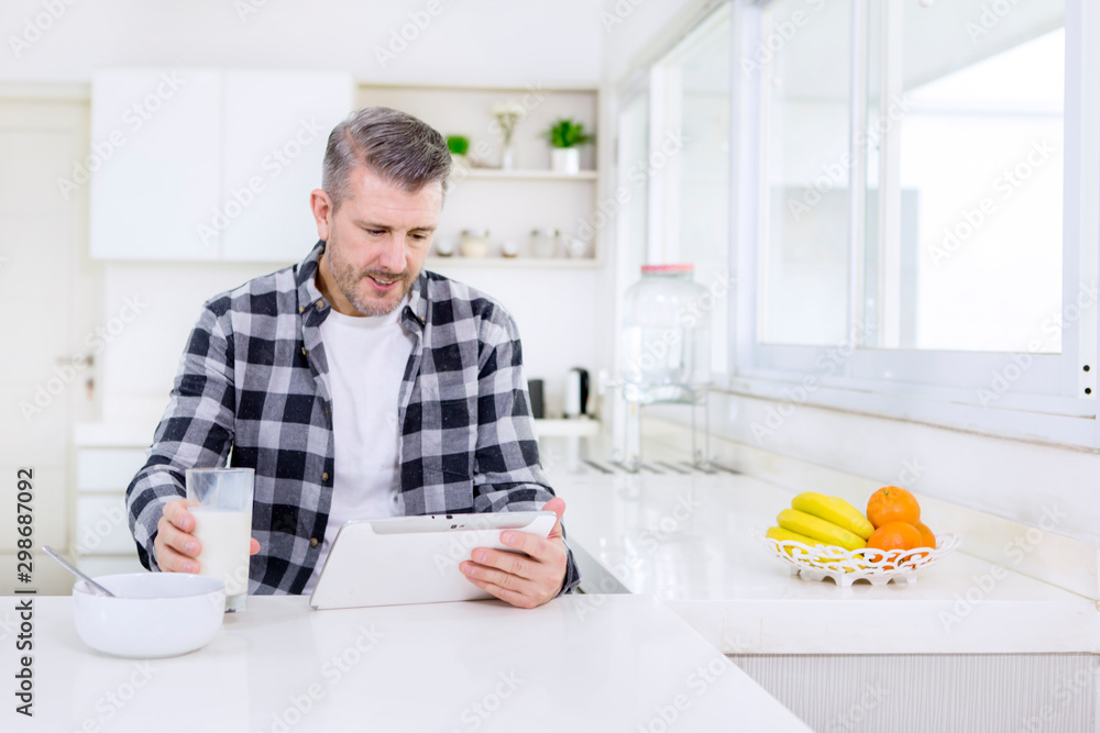 Caucasian man holding milk while using a tablet Caucasian man holding milk while using a tablet