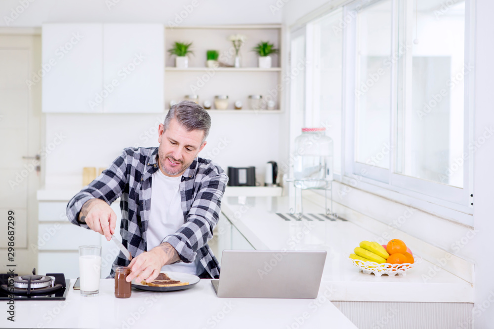 Caucasian man making breakfast while working Caucasian man making breakfast while working