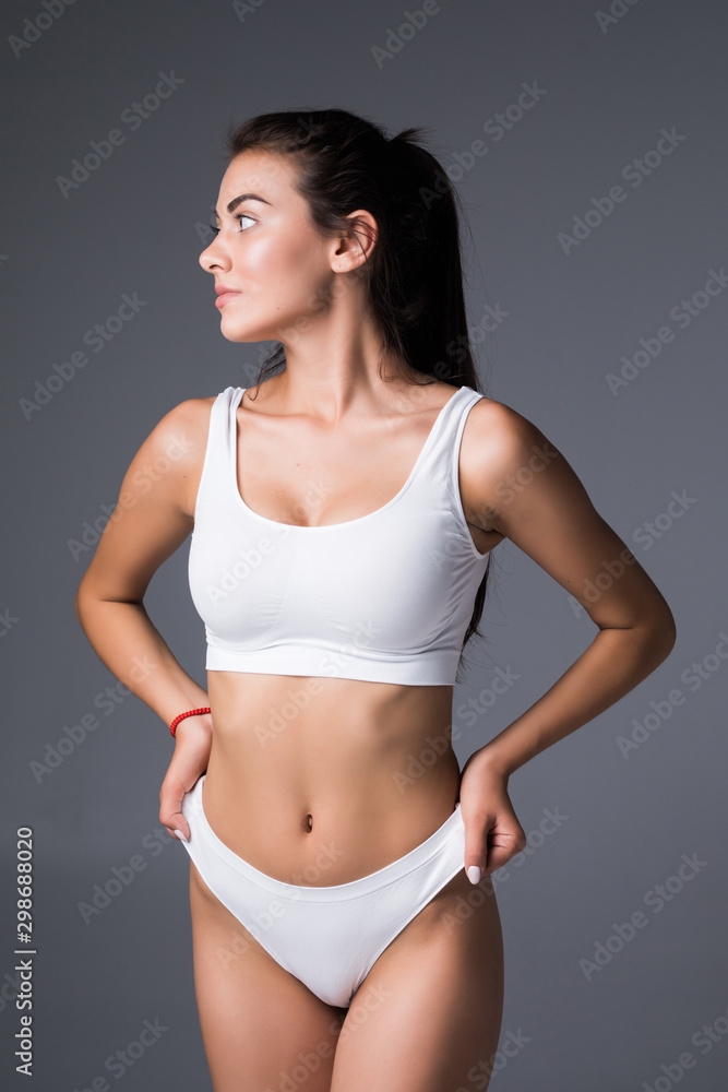 Fototapeta premium Young, sporty, fit and beautiful girl over grey background.