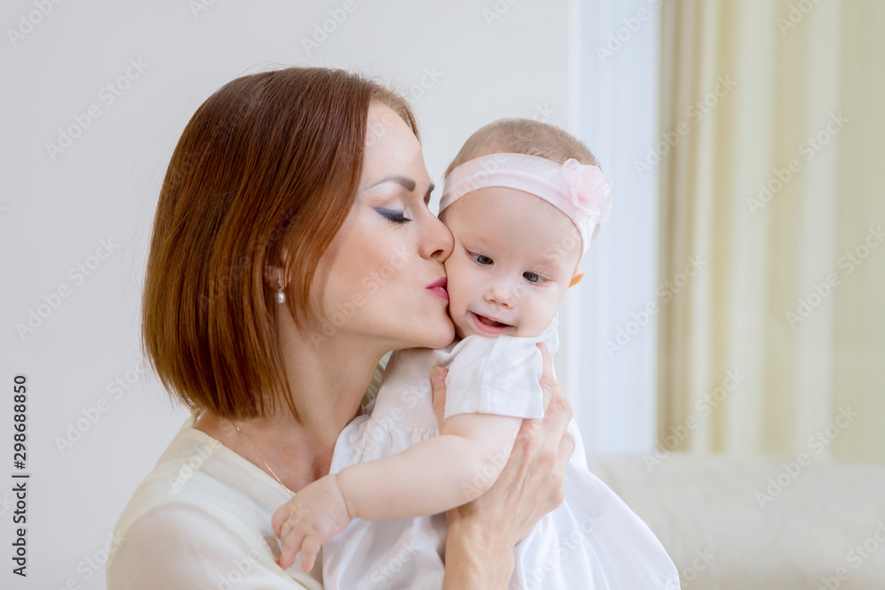 Caucasian woman kissing her baby cheek at home Caucasian woman kissing her baby cheek at home