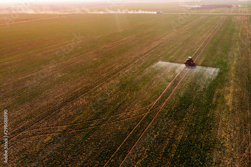 Tractor spraying fertilizer or pesticides on field with sprayer