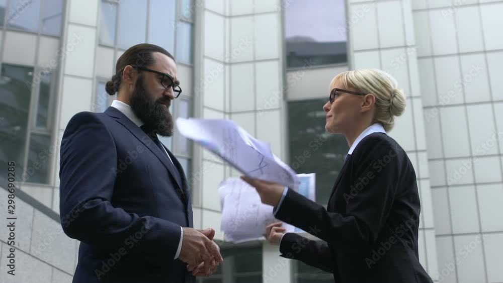 Nervous businesswoman throwing papers in front of male colleague, stressful job Nervous businesswoman throwing papers in front of male colleague, stressful job