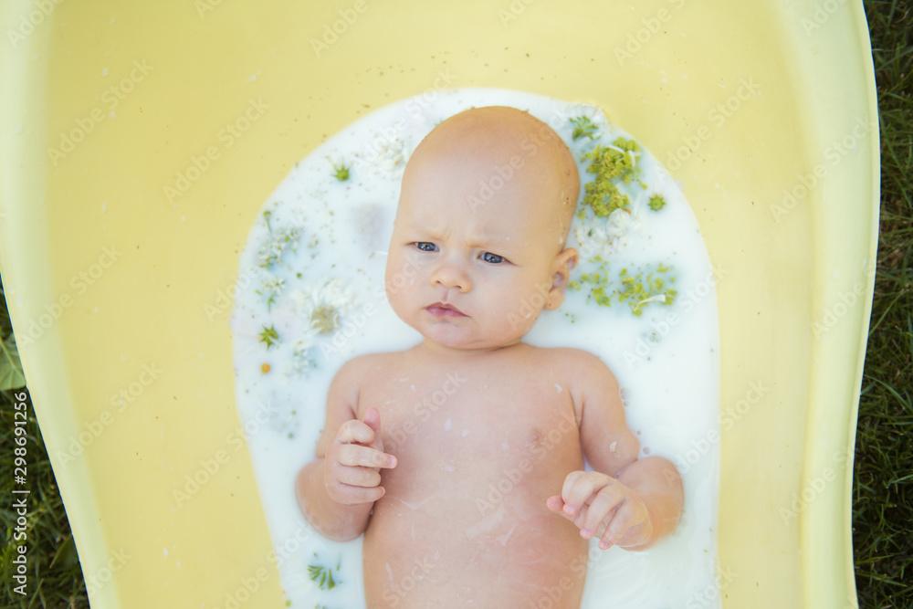 Close up of a baby in milk bath with natural flowers Close up of a baby in milk bath with natural flowers