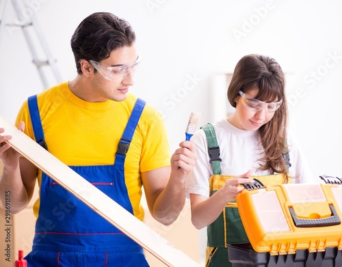 The man explaining woman woodworking tips in wood workshop