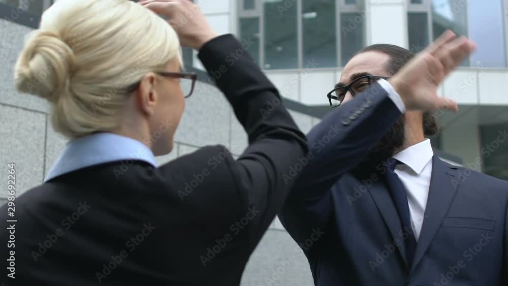 Woman and man in formalwear making high-five gesture, celebrating success, deal Woman and man in formalwear making high-five gesture, celebrating success, deal