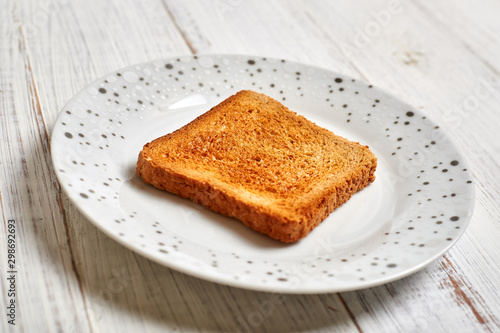 Toasted white toast on a plate on a light wooden background.