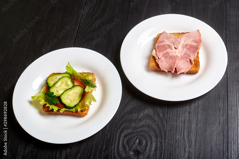 Sandwich with vegetables and a sandwich with meat. The choice between vegetarianism and meat-eating. Sandwich with vegetables and a sandwich with meat. The choice between vegetarianism and meat-eating.