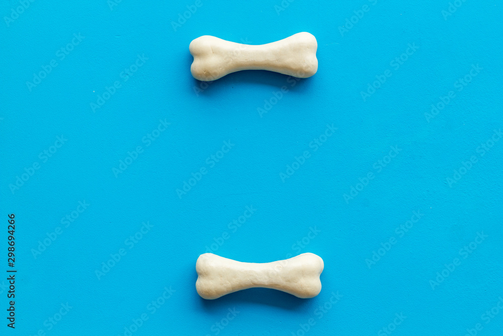 Obraz premium Food and toys for dogs. Chewing bones on blue background top view space for text