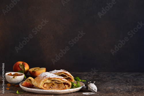 Apple strudel with cinnamon, nuts and and raisins on a dark concrete background.