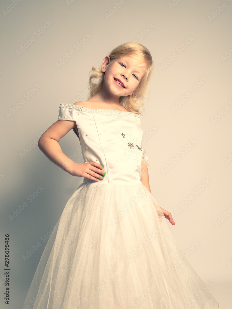 little girl in a wedding dress. pretty little girl in beautiful white dress isolated on light background