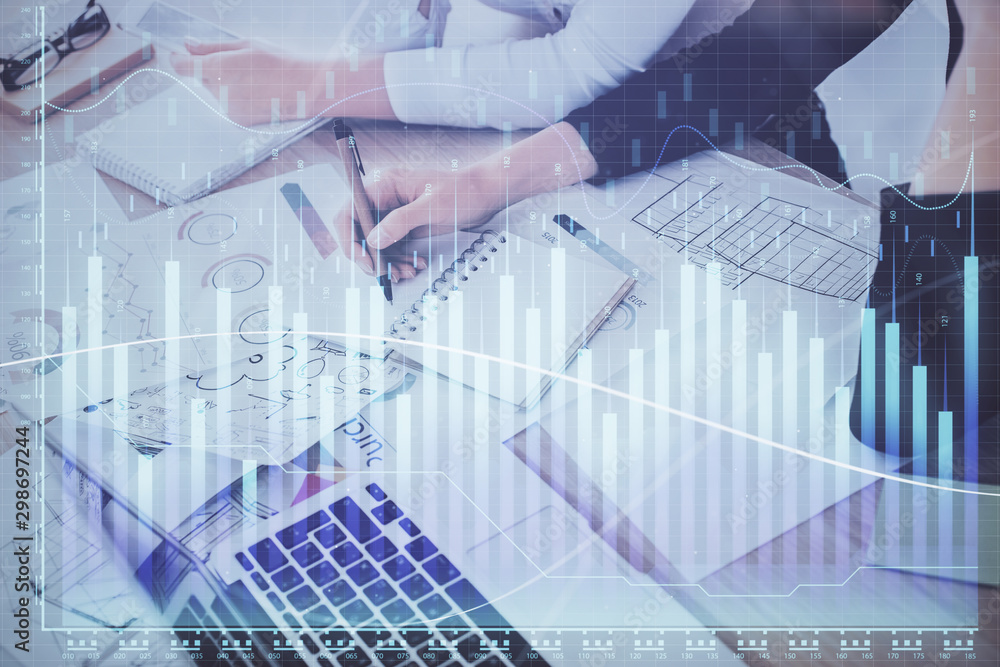 A woman hands writing information about stock market in notepad. Forex chart holograms in front. Concept of research. Double exposure A woman hands writing information about stock market in notepad. Forex chart holograms in front. Concept of research. Double exposure