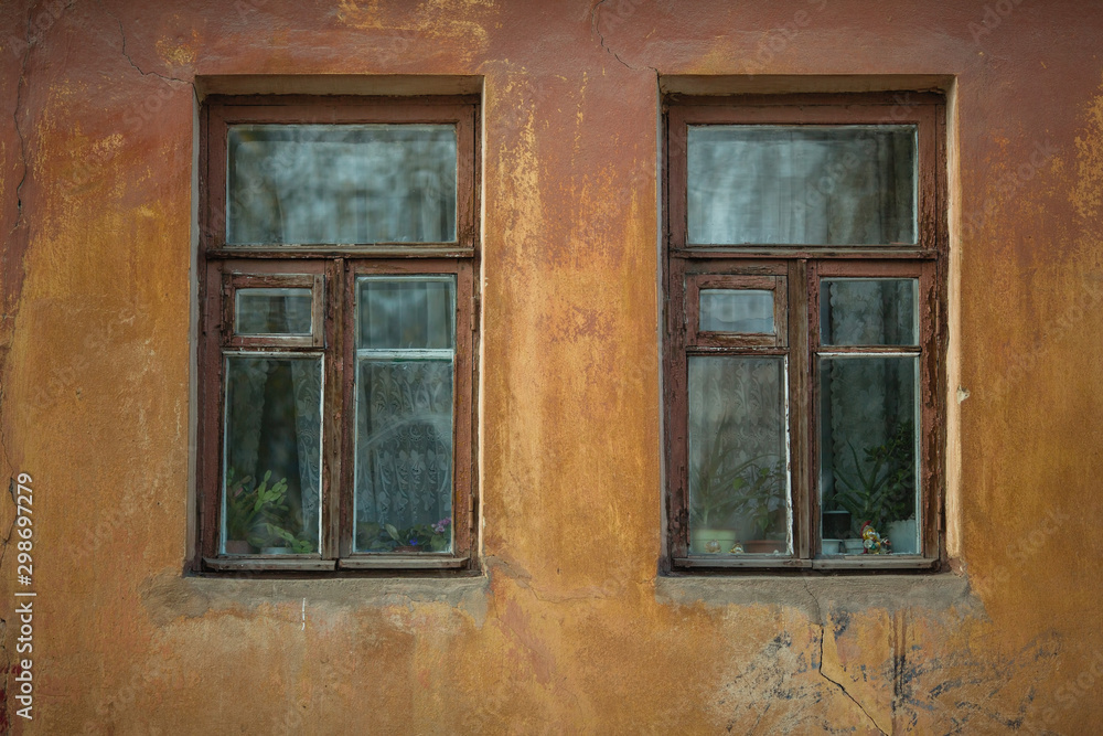 Two windows on the facade of an old stone house.