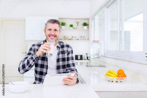 Happy man using a tablet after breakfast in kitchen