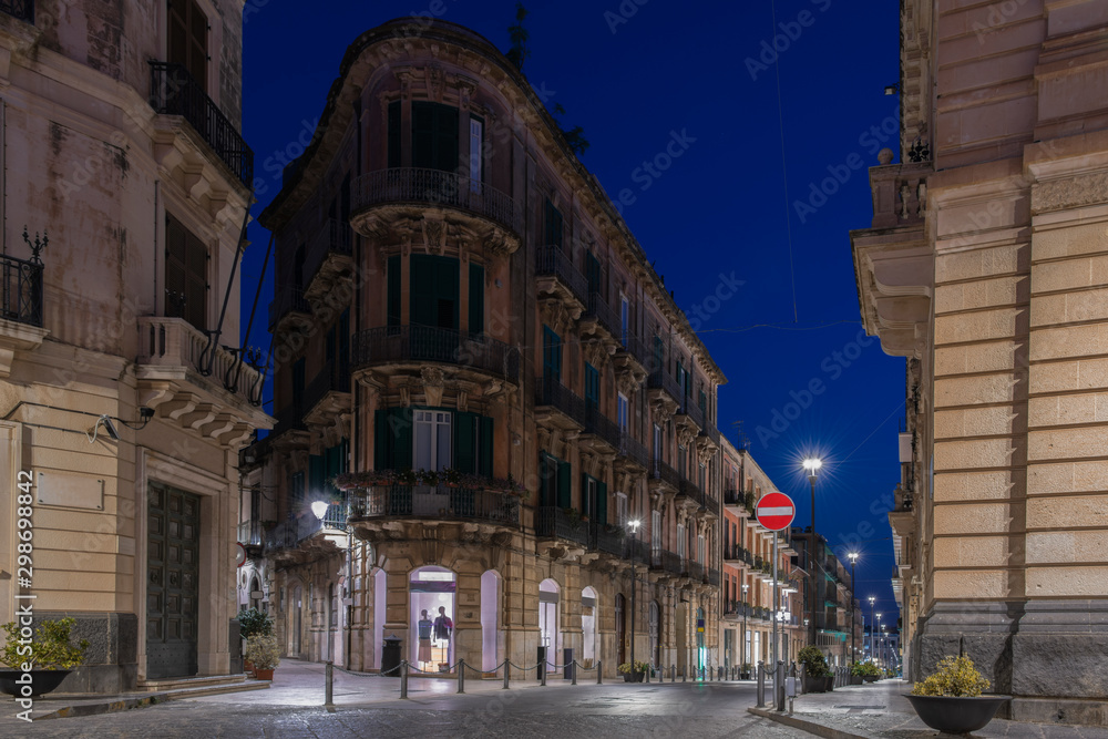 Facades of the buildinngs and urban street at night in the Ortygia island, Syracuse in Sicily, Italy