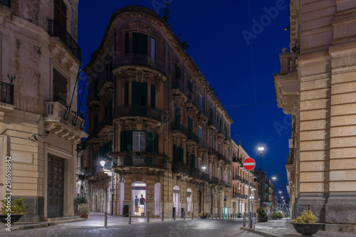 Facades of the buildinngs and urban street at night in the Ortygia island, Syracuse in Sicily, Italy © Andrii Shnaider