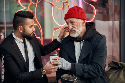 Quadro su tela merciful businessman sit next to tramp in red hat and coat, rich man in black tu