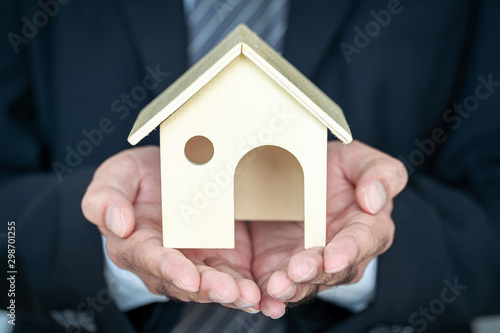 Businessman hand holding a model home presenting on white background, Saving money for buy a new house or loan for plan business investment of real estate concept.
