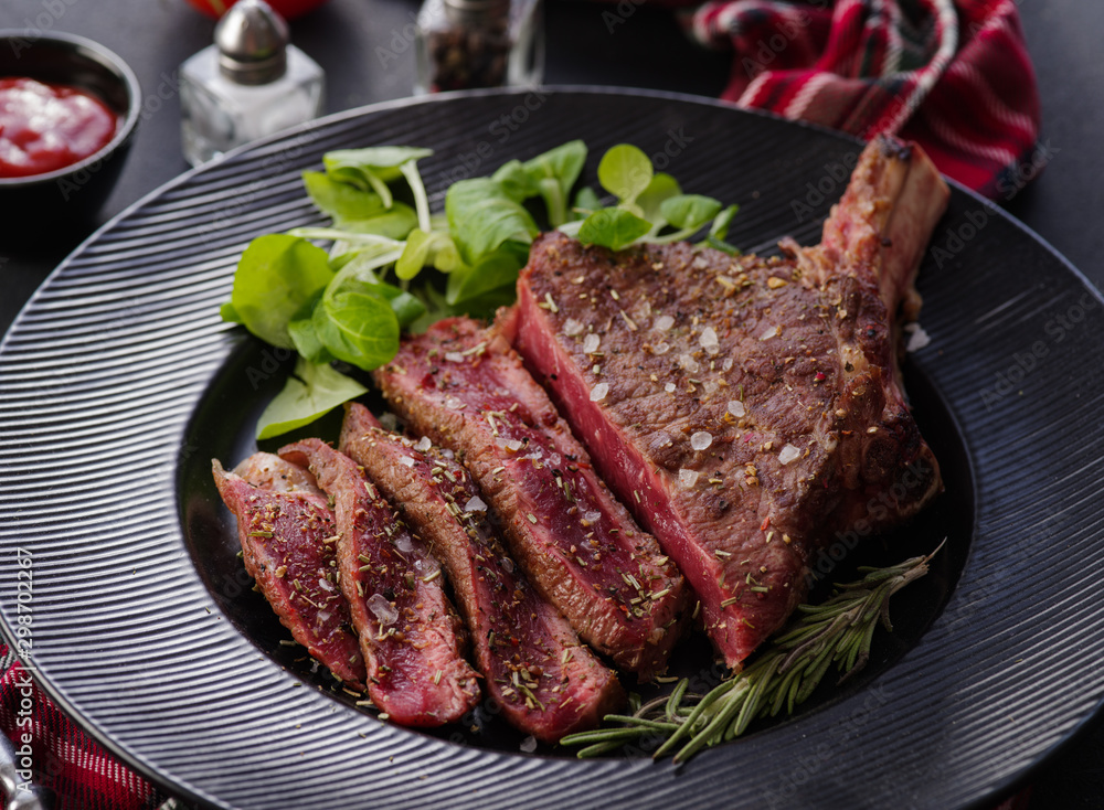 Steak on the bone. Rib eye. Tomahawk steak on the black plate with ...