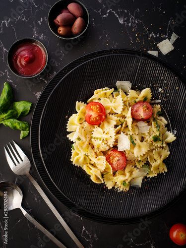 Farfalle pasta with parmesan, basil and cherry tomatoes. Italian Cuisine. Top view photo