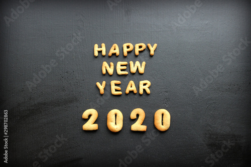 2020 new year background. Baked letters Happy New year and numbers 2020, stars, snowflakes on a black background.Greeting card with gingerbread. Card with New year from gingerbread on a wooden black t