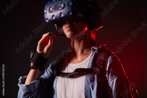 Young female stand listening on radio set, playingvirtual game isolated over black background