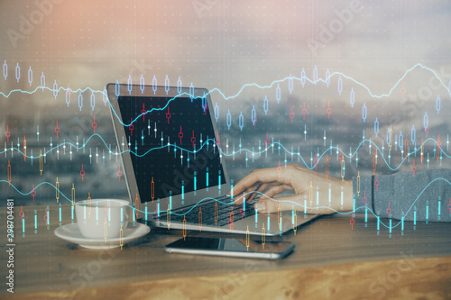 Double exposure of businessman s hands with laptop and stock market graph background. Concept of research and trading.