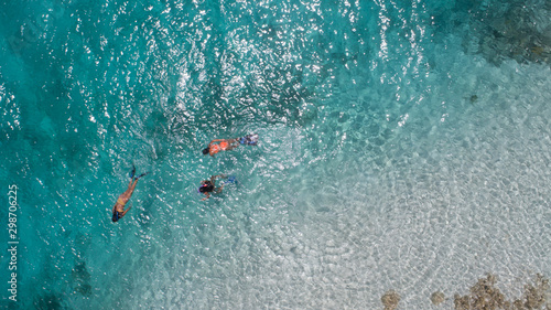 Three young girls snorkeling in blue waters above coral reef  in tropical Caribbean sapphire crystal clear calm waters  People and lifestyle concept