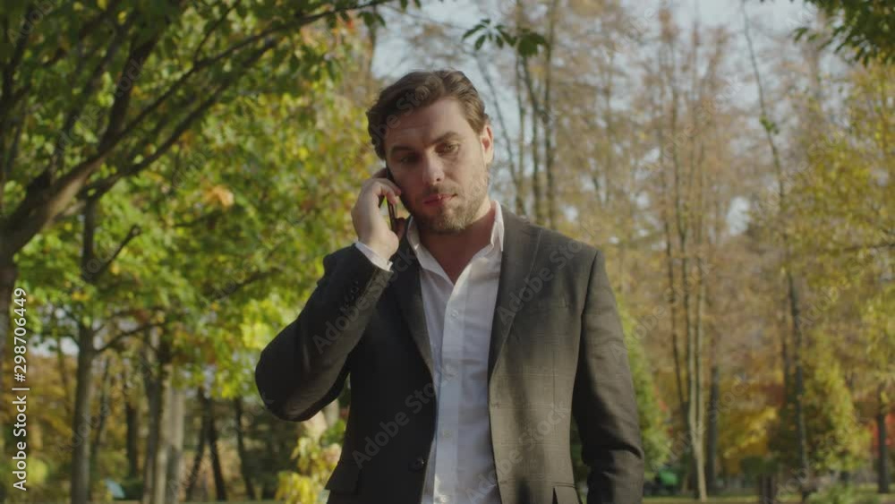 A man conducts telephone conversations with a serious look on the background of the autumn landscape A man conducts telephone conversations with a serious look on the background of the autumn landscape