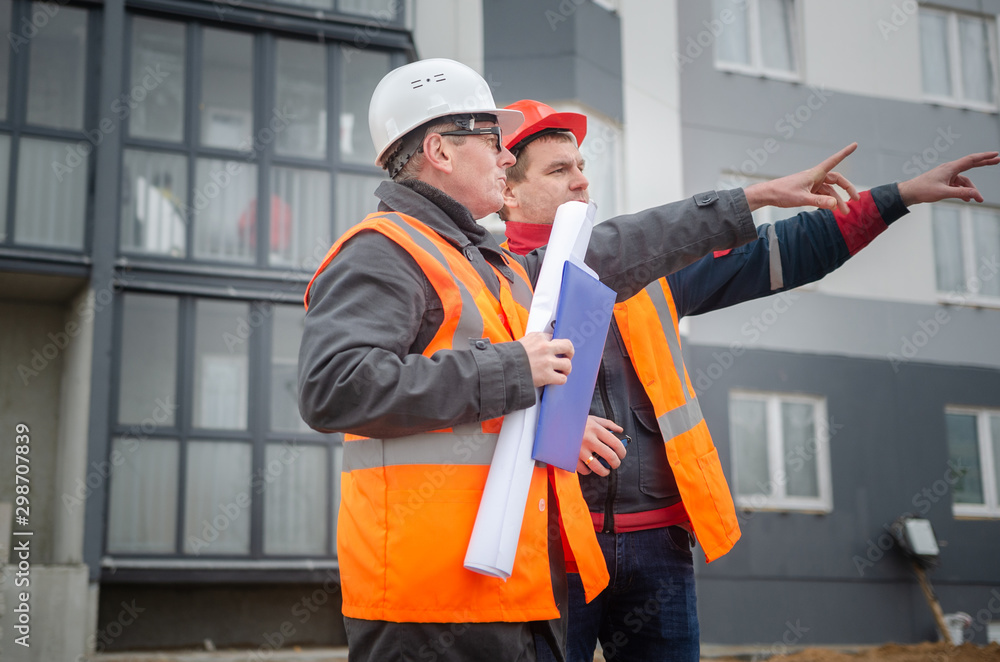 An engineer with a hard hat and helmet discussing a project at a construction site with a team leader. architecture construction concept. Industrial safety