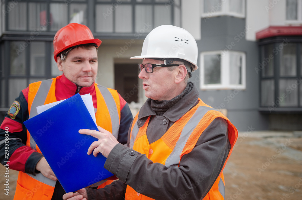 An engineer with a hard hat and helmet discussing a project at a construction site with a team leader. architecture construction concept. Industrial safety An engineer with a hard hat and helmet discussing a project at a construction site with a team leader. architecture construction concept. Industrial safety