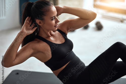 Attractive fit female pump press in gym. Fitness girl in black sportswear exercising
