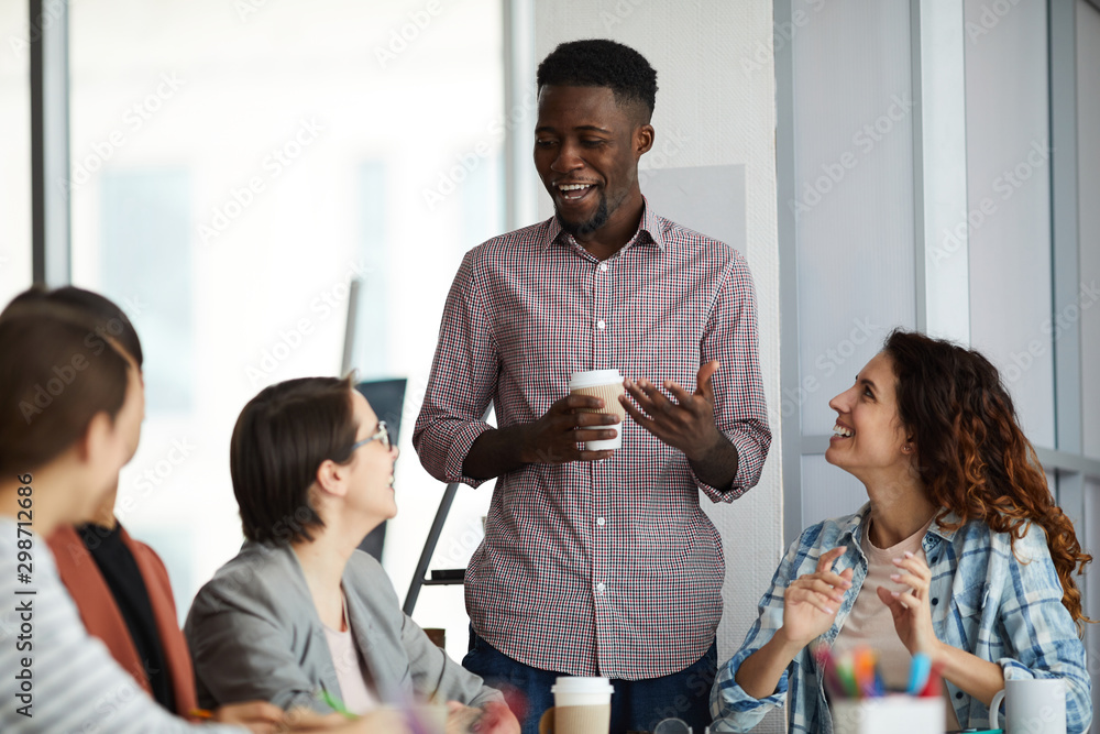 Portrait of young African-American man presenting ideas to creative team during meeting in office, copy space Portrait of young African-American man presenting ideas to creative team during meeting in office, copy space
