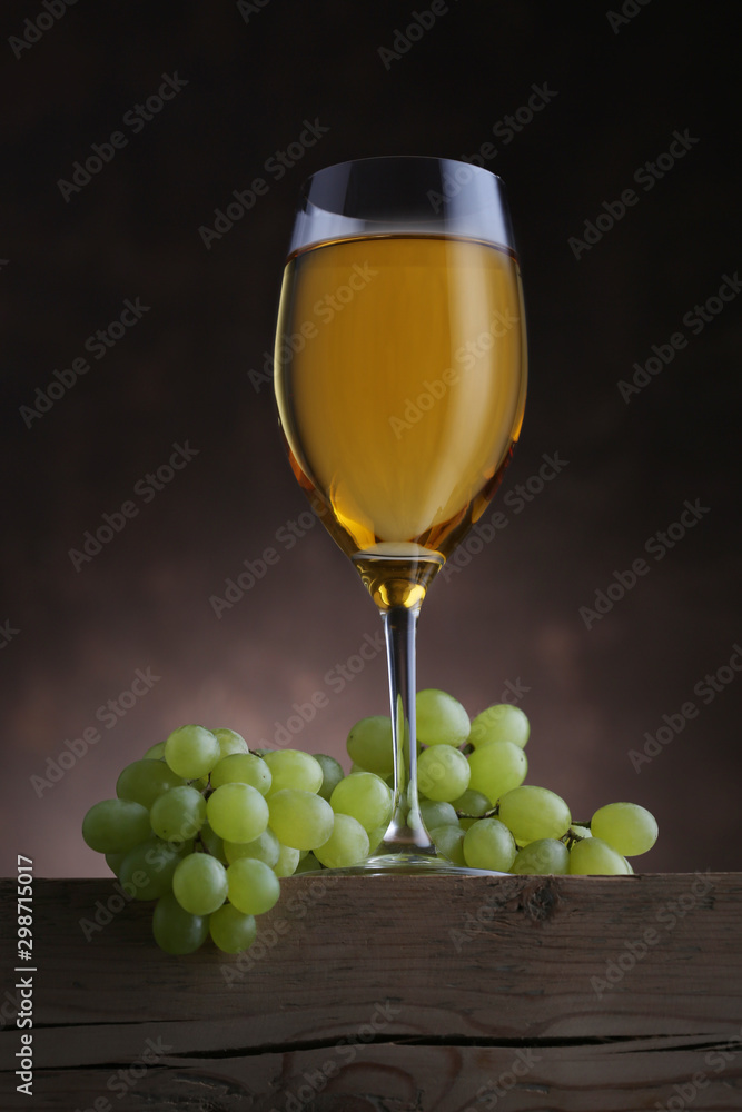 Glass of white wine with grape on wooden table Glass of white wine with grape on wooden table