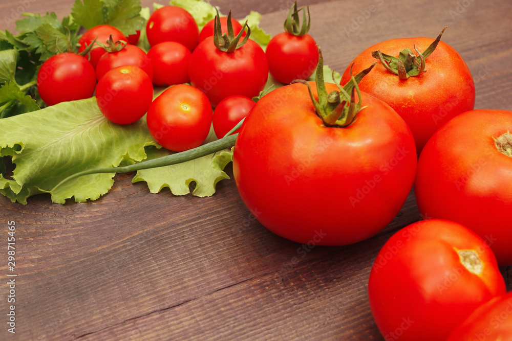 Fresh summer tomatoes and greens on a rustic table Fresh summer tomatoes and greens on a rustic table
