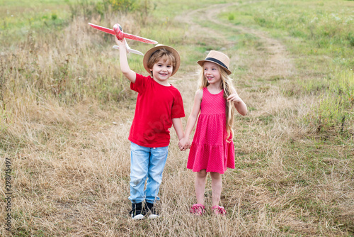 Valentines day concept. Happy kids - sister and brother on summer field. Cute children walking in the wheat golden field on a sunny summer day. Adventure and vacations children concept.